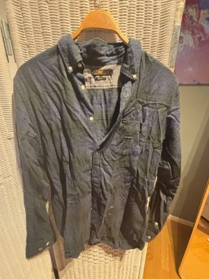 Blå långärmad skjorta från Lee - Snygg blå skjorta från Lee med klassisk krage och knappstängning framtill. Skjortan har en bröstficka med diskret Lee-logga och är tillverkad i ett mjukt bomullstyg. Perfekt för en avslappnad men stilren look.