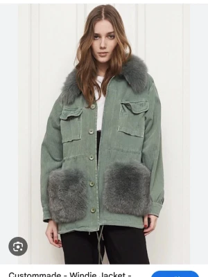 Grön pälsjacka med stora fickor - Skicka bud!! Minsta storleken som är S/M Snygg grön pälsjacka från Custommade med stora fluffiga pälsdetaljer på kragen och fickorna. Jackan har knappar framtill, två bröstfickor med lock och två stora fickor nedtill. Oversized passform och cool vintagekänsla.