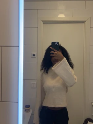 Vit croppad stickad tröja - Säljer en vit croppad stickad tröja med vida ärmar och enkel design. Tröjan har en mjuk och avslappnad passform, perfekt för en trendig och bekväm stil. Passar till både jeans och kjol för en snygg vardagslook.