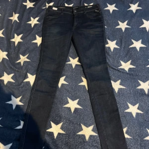Mörkblå skinny jeans från Replay - Säljer ett par mörkblå skinny jeans från Replay med klassisk femficksdesign och låg midja. Jeansen har en smal passform och är tillverkade i stretchigt denimtyg för extra komfort. Perfekta för en trendig och avslappnad look.