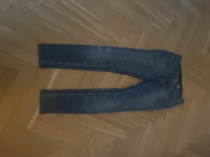 Tiger of Sweden jeans Blå - Säljer ett par klassiska blå jeans från tiger of sweden med snygga slitningar. Jeansen har fem fickor, guldfärgade sömmar och en ljus tvätt som ger en cool look. Passar perfekt till sneakers och hoodie för en avslappnad stil. Hör av dig vid minsta intresse ⭐️⭐️