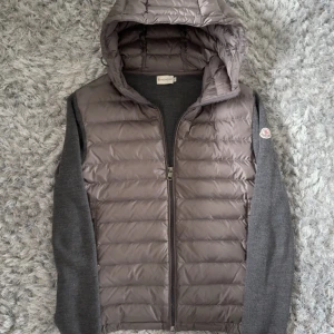 Grå dunväst med huva från Moncler - Moncler Maglione Tricot Cardigan Grå  Skick: 9/10 Nypris: 12000kr+ Pris: 5990kr Frakt: (Hemlevererat spårbart)📦  110+ referenser tillgängliga, tveka inte meddela ifall du är intresserad! Wluxury1 på Instagram!