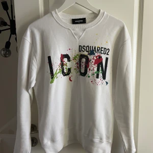 Vit sweatshirt från Dsquared2 ICON - Vit sweatshirt från Dsquared2 i storlek S med färgstänk och stor svart ICON-print på bröstet. Tröjan har rund hals, långa ärmar och är tillverkad i mjuk bomull. Väldigt bra skick. 
