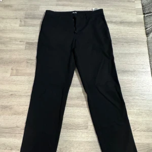 Svarta raka kostymbyxor - Svarta kostymbyxor med rak passform och klassisk design. Perfekta för en stilren look och passar till skjorta eller t-shirt. Materialet är mjukt och följsamt. Storlek W32/L34