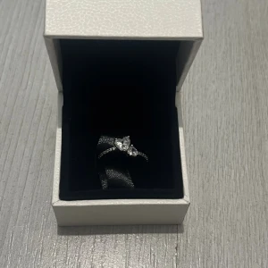  Pandora ring  - Säljer en elegant silverring från Pandora med en gnistrande hjärtformad sten och små stenar längs ringen. Kommer i original ask. Perfekt för dig som vill ha något stilrent men ändå glittrigt.