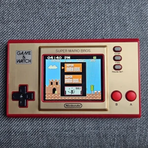 Game & Watch: Super Mario Bros. - Nintendo Game & Watch: Super Mario Bros. med färgskärm. Innehåller klassiska spel som Super Mario Bros., Super Mario Bros. 2 och Ball. Konsolen och kartongen är i mycket gott skick, med endast mindre slitage på kartongen. Perfekt för samlare och retrospel-entusiaster.