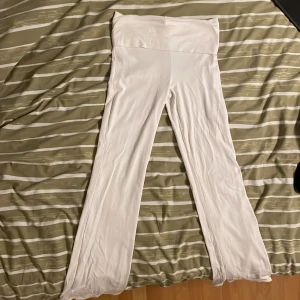 Vita yoga pants från Gina Tricot - Säljer ett par vita, vida byxor från Gina Tricot. Byxorna har hög midja och är tillverkade i ett mjukt och stretchigt material som känns riktigt skönt mot huden. Perfekta för en chill och trendig look.