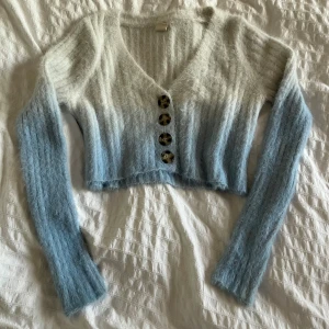 Ljusblå croppad kofta med knappar - Mjuk och fluffig croppad kofta i ljusblått och vitt med ombre-effekt. Passar XS-S