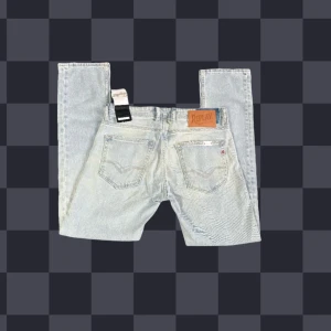 Replay Grover jeans - Helt nya! Snygga ljusblå jeans från Replay med klassisk femficksdesign och raka ben. Jeansen har läderpatch bak, diskreta slitningar och är tillverkade i mjukt denimtyg. Passformen är straight och de har normal midja. Perfekta för en avslappnad och trendig look. Modell Grover. Midja 42cm, längd 105cm, bevnidd 17,5cm. Jag skickar inga fler bilder när jag bär jeansen än den befintliga :)