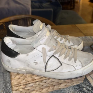 Philippe Model vita mocka skor - Snygga vita sneakers från Philippe Model.Skorna har snörning, rund tå och är tillverkade i skinn med en klassisk låg siluett. Perfekta för dig som gillar en stilren och trendig look. Lite slitna med hål vid hälen som man kan se vid bild 5. Har satt in lagning och lagningskit skickas med. Kvitto finns priset kan diskuteras lite