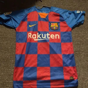 FC Barcelona Messi 10 matchtröja Nike - Säljer en officiell FC Barcelona fotbollströja från Nike med Messi 10-tryck på ryggen. Tröjan har klassiskt rutigt mönster i rött och blått, korta ärmar och klubbmärke på bröstet. Materialet är lätt och andas, perfekt för fotboll eller samling.
