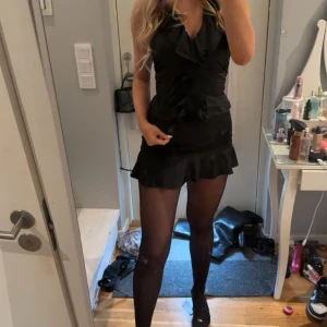 Svart kort volangkjol - Supersnygg svart minikjol med volangdetalj längst ner på kjolen. Materialet är glansigt och känns lyxigt, perfekt för att sticka ut. Passar dig som gillar trendiga och feminina plagg. Den är lågmidjad. Köpt i Australien på Glassons nypris 349kr💕säljer även toppen