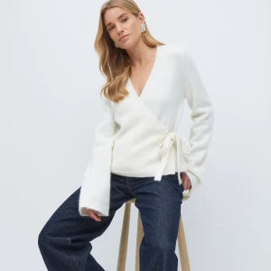 Vit omlottkofta med knyt i sidan - Superfin vit omlottkofta med v-ringning och knyt i sidan. Koftan är stickad och har långa ärmar med lite lösare passform. Perfekt att slänga på sig över ett linne eller t-shirt för en chill look. Orginalpris 399kr