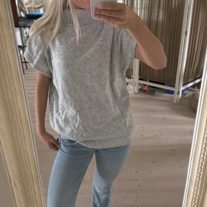 Grå polotröja med korta ärmar - Säljer en grå polotröja med bred ribbad krage och korta ärmar. Tröjan har en loose passform och är stickad i mjukt material. Pris kan diskuteras 