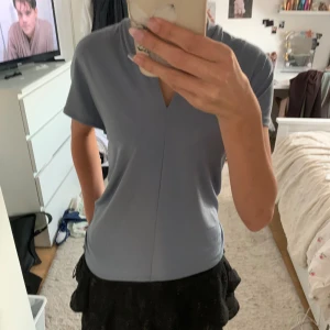 Ljusblå v-ringad topp med kort ärm - Säljer en stilren ljusblå topp med v-ringning och korta ärmar. Toppen har en rak passform och är enkel men ändå snygg, perfekt att matcha med kjol eller jeans. Materialet känns mjukt och följsamt mot huden.