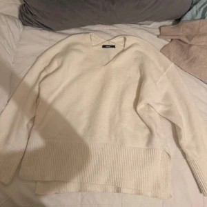 Vit stickad v-ringad tröja BikBok - Mysig vit stickad tröja från BikBok i storlek S. Tröjan har v-ringning, långa ärmar och bred ribbad kant nedtill och vid ärmsluten. Perfekt för lager-på-lager och chill dagar.