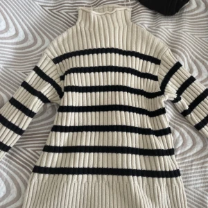 Randig ribbstickad halvpolotröja från Zara - Ribbstickad halvpolotröja från Zara i beige med svarta ränder. Tröjan har hög krage, lång ärm och slits vid ärmslut. Den är stickad i ett mjukt material och har en loose passform som ger en chill vibe. Pris kan diskuteras 