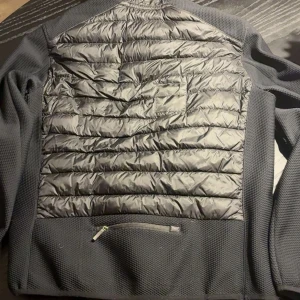 Svart hybridjacka från Parajumpers - Snygg svart hybridjacka från Parajumpers med quiltad framsida och rygg i glansigt material, samt ärmar och sidor i stretchig mesh. Jackan har dragkedja framtill, bröstficka med dragkedja och Parajumpers-logga på ärmen. Perfekt för lager-på-lager under kyliga dagar.