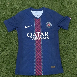 PSG matchtröja Nike Dri-FIT ADV  - Paris Saint-Germain fotbollströja i mörkblått med röd och vit rand längs mitten, PSG-emblem på bröstet och Nike-logga. Tillverkad i lätt, ventilerande Dri-FIT ADV-material. Snyggt geometriskt mönster på framsidan och Qatar Airways-tryck.