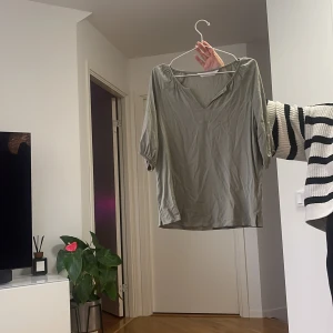 Ljusgrön v-ringad blus - Säljer en ljusgrön blus med v-ringning och halvlånga ärmar. Blusen har en avslappnad passform och är tillverkad i ett mjukt, tunt material som känns skönt mot huden. Perfekt att styla med jeans eller kjol för en enkel och snygg look.