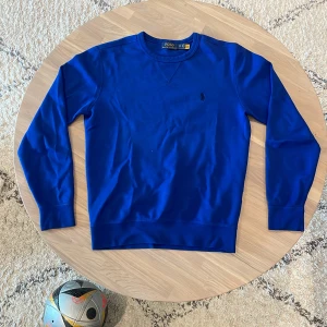 Blå sweatshirt från Polo Ralph Lauren XS - Klassisk blå sweatshirt från Polo Ralph Lauren i storlek XS. Tröjan har rund halsringning, långa ärmar och den ikoniska broderade loggan på bröstet. Tillverkad i mjuk bomull för en skön och avslappnad stil.