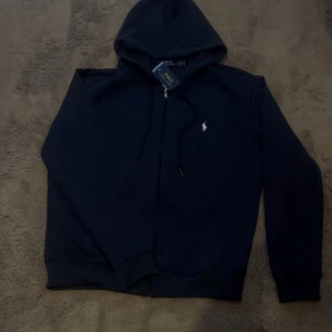  Polo zip up marine blue - Polo Zip-Up Hoodie mörk blå – Storlek M  ✅  – tag kvar, men kvitto saknas 🧼 Helt oanvänd – inga märken, fläckar eller skador 📦 Originalpåse saknas, men skickas väl emballerad  ⚠️ Säljes p.g.a. fel storlek 📍 Möts upp i Göteborg eller skickas spårbart  Skicka ett meddelande om du är intresserad eller har frågor!