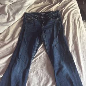 Mörkblå jeans från Gina Tricot 170 - Snygga mörkblå jeans från Gina Tricot med kontrasterande vita sömmar och dekorativa ficklock med knappar både fram och bak. Klassisk femficksmodell i stretchigt jeanstyg, perfekt för dig som gillar en cool och tidlös look.Finns en liten spriumellan bennen men jätte lätt att sy och syns typ ej därav priset 