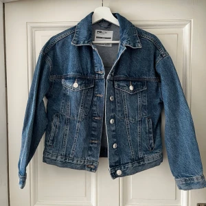 Klassisk blå jeansjacka FB Sister XS - Snygg blå jeansjacka från FB Sister i klassisk modell med knappar framtill och två bröstfickor. Jackan har en rak passform, krage och långa ärmar. Perfekt för lager-på-lager och enkel att styla till olika outfits.