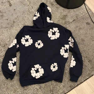 Mörk blå hoodie med blommönster från Denim Tears - Säljer min mörk blå denim tears A COPIA hoodie och byxor. Båda kostar mindre än en MC beställning, dem är i okej skick, båda hoodie och byxor för 150kr. Båda är M i storlek. Jag har på mig S och dem var stora för mig, därför säljer jag för långt och snabbt pris.