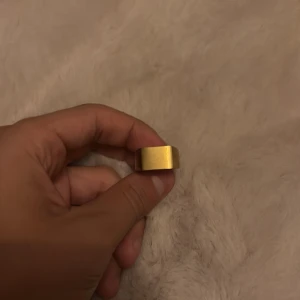 Bred guldfärgad ring i minimalistisk stil - Säljer en bred och stilren ring i guldfärg med matt finish. Ringen har en modern, kantig form och känns riktigt chunky och cool. Perfekt för dig som gillar minimalistiska accessoarer med statement-känsla.
