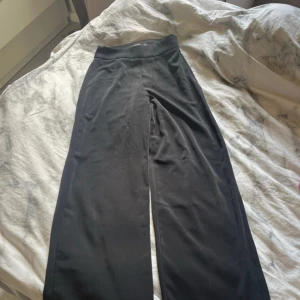 Svarta vida byxor från Bik Bok - Svarta byxor från Bik Bok i storlek 34. De har hög midja och ett rakt, lite vidare ben som ger en snygg och avslappnad look. Byxorna är tillverkade i ett mjukt och stretchigt material som känns bekvämt hela dagen.
