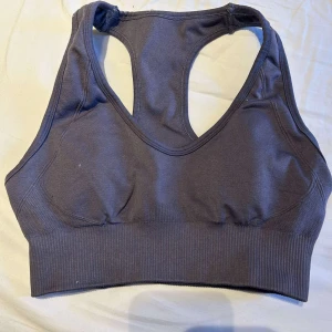 Mörkgrå sporttopp från ICANIWILL - Säljer en mörkgrå sporttopp från ICANIWILL med brottarrygg och bred resår nedtill. Toppen är sömlös och tillverkad i ett stretchigt material som ger bra stöd vid träning. Perfekt för gymmet eller löprundan.