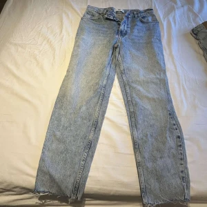 Ljusblå raka jeans med råa kanter - Snygga ljusblå jeans med raka ben och råa, fransiga kanter nertill. Klassisk femficksmodell i denim som ger en avslappnad vibe. Perfekta till sneakers eller boots för en cool look.