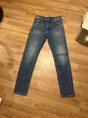 Replay blå  jeans storlek 25 - Snygga blå jeans från Replay i modellen Marty, storlek 25. Jeansen har en klassisk femficksdesign, smal passform och är tillverkade i mjukt bomullsmaterial med lite stretch. Perfekt tvättad look med ljusare partier på låren och bakfickor med Replay-logga.