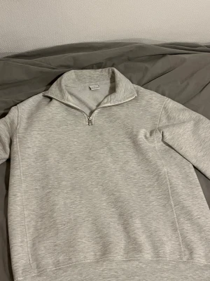 Ljusgrå half/quarter zip tröja från Zara - Säljer en stilren ljusgrå tröja från Zara i storlek S. Tröjan har en klassisk half zip-dragkedja vid kragen och är långärmad. Materialet är mjukt och känns som bomull, perfekt för chill dagar. Enkel design utan mönster eller extra detaljer.