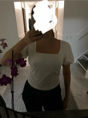 Vit blus med puffärm och fyrkantig hals - Säljer en vit blus med puffärmar och snygg fyrkantig halsringning. Toppen har en lätt ribbad struktur och är figurnära i passformen. Perfekt att styla med jeans eller kjol för en trendig look. Materialet känns mjukt och bekvämt mot huden.