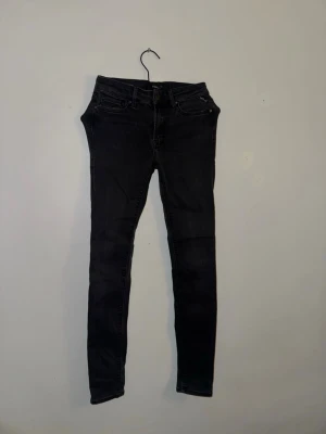Svarta skinny jeans från Replay  - Svarta jeans med klassisk femficksdesign och smal passform. Byxorna har midwaist och är tillverkade i stretchigt jeansmaterial för en bekväm känsla. Perfekta för dig som gillar en tight siluett och enkel stil.