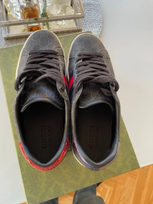 Gucci sneakers med röd och lila detalj - Säljer nu mina Gucci ace skor fick hem dem igår icke äkta men väldigt bra kvalité men säljer pga att dom va lite för små för min åsikt så yes men väldigt bra kvalité nästan till 100% som dom äkta så ingen kommer märka något. Dom är använda en gång och det var igår när jag fick hem dom.