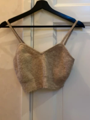 Beige stickad linnetopp från H&M - Säljer en beige stickad linnetopp från H&M i storlek S. Toppen har smala axelband och en croppad passform med ribbad struktur. Perfekt för att styla med höga jeans eller kjol. Supermysig och trendig för varmare dagar!