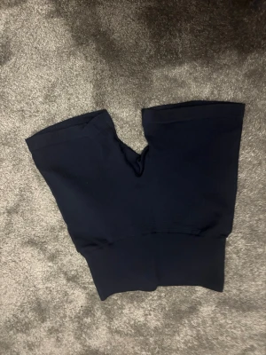 Mörkblå träningsshorts XXS - Säljer ett par mörkblå träningsshorts från SOC i storlek XXS. De är högmidjade och har en diskret logga baktill. Materialet är stretchigt och består av 96% polyamid och 4% elastan, vilket gör dem riktigt sköna för gymmet eller löpning.
