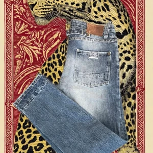 Blå jeans från Superdry, storlek 32/32 - Snygga blå jeans från Superdry med klassisk femficksdesign och slitna detaljer. Jeansen har en rak passform, normal midja och Superdry-logga på fickan. Materialet är robust denim i bomull och färgen är en tvättad blå ton med ljusare partier.