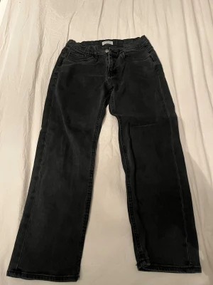 Svarta jeans från Lindex, strl 152 - Svarta jeans från Lindex med klassisk femficksdesign och knappstängning. Jeansen har en rak passform och är tillverkade i bomullsmaterial med lite stretch. Snygga att matcha med sneakers eller boots för en chill look.