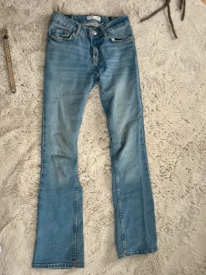 Blå bootcut jeans från Bershka - Säljer ett par blå jeans från Bershka med låg midja och klassisk bootcut-passform. Jeansen är i storlek 34 men är insydda med 1 cm i midjan, så midjemåttet från sida till sida är 33cm istället för 34. 💕 jeansen är i bra skick och den enda defekten man ser lite är som ni ser på näst sista bilden, där nere längst ner är den en liten liten missfärgning eller fläck men inget man tänker på överhuvudtaget enligt mig. 