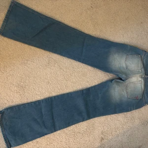 Levi's 517 bootcut jeans blå - Säljer ett par klassiska Levi's 517 jeans i blå tvätt med snygga slitningar och bootcut-ben. Jeansen har fem fickor, knappgylf och den ikoniska Levi's-lappen på bakfickan. Perfekt för dig som gillar retrostil och bredare benslut.