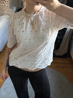 Vit broderad blus - Säljer en vit blus med broderade blommor och hålmönster. Däremot en liten reva på baksidan men absolut inget man tänker på!