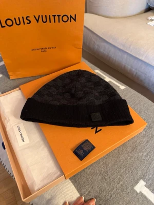  Louis Vuitton Neo Petit Damier Mössa  - Snygg svart Neo Petit Damier mössa från Louis Vuitton. Har använt den relativt mycket och har ägt den i ca 2 år. Säljer för kommer inte till användning längre 😔 perfekt för dig som gillar designeraccessoarer 😁 (snabb affär - bättre pris)