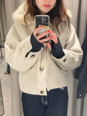 Beige teddyjacka med fuskpäls - Säljer en helt my beige teddyjacka med fluffig fuskpäls på kragen och snygga knappar framtill. Jackan har två stora fickor med lock och en croppad passform som ger en cool vibe. Perfekt för dig som vill ha en mysig och trendig jacka i höst och vinter.
