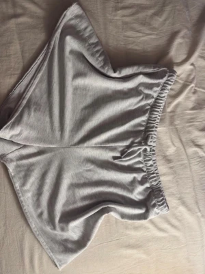 Grå loose shorts med resårmidja - Säljer ett par gråa shorts med loose passform och bekväm resår i midjan. Perfekta för chill dagar eller när du vill ha något enkelt och skönt på dig. Materialet är mjukt och känns som bomull, vilket gör dem riktigt sköna att bära.