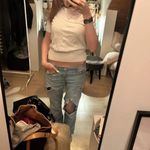 Vit stickad t-shirt med bred smock / resår i bomull - Säljer en enkel och fräsch vit t-shirt med croppad passform. T-shirten har korta ärmar och är gjord i mjuk bomull, perfekt till jeans eller kjol. Stilren och lätt att matcha med andra plagg.