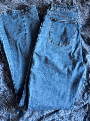 Blå raka jeans från Neuw, storlek 24 - Säljer ett par klassiska blå jeans från Neuw i rak modell. Jeansen har hög midja, fem fickor och snygga kopparfärgade detaljer vid knappar och dragkedja. Materialet är robust denim i bomull och passformen är normal. Perfekta för en chill och stilren look.